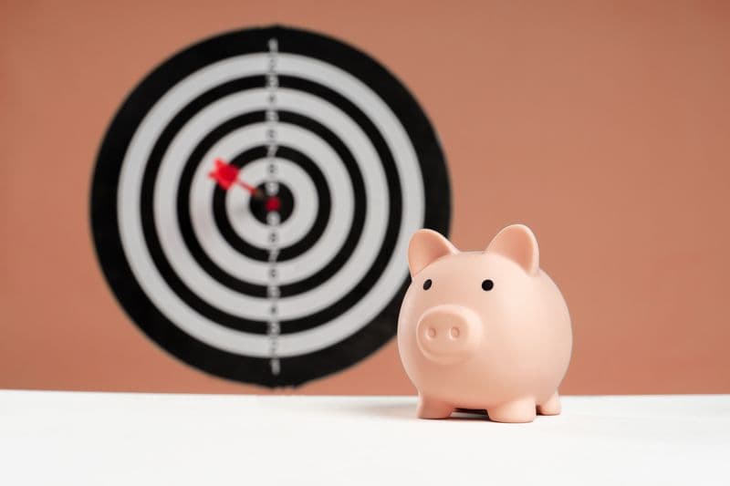 Piggy bank in front of a dartboard symbolising savings targets