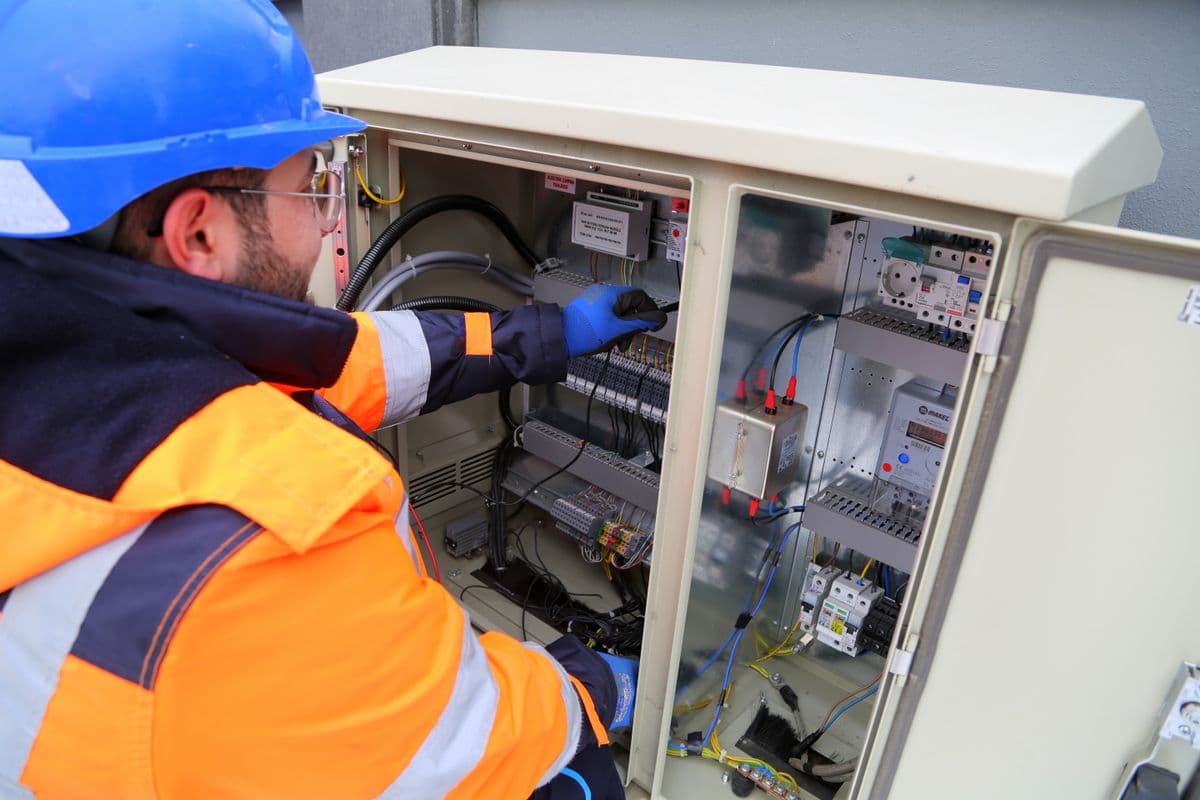 Electrician in safety gear working on an outdoor electrical panel