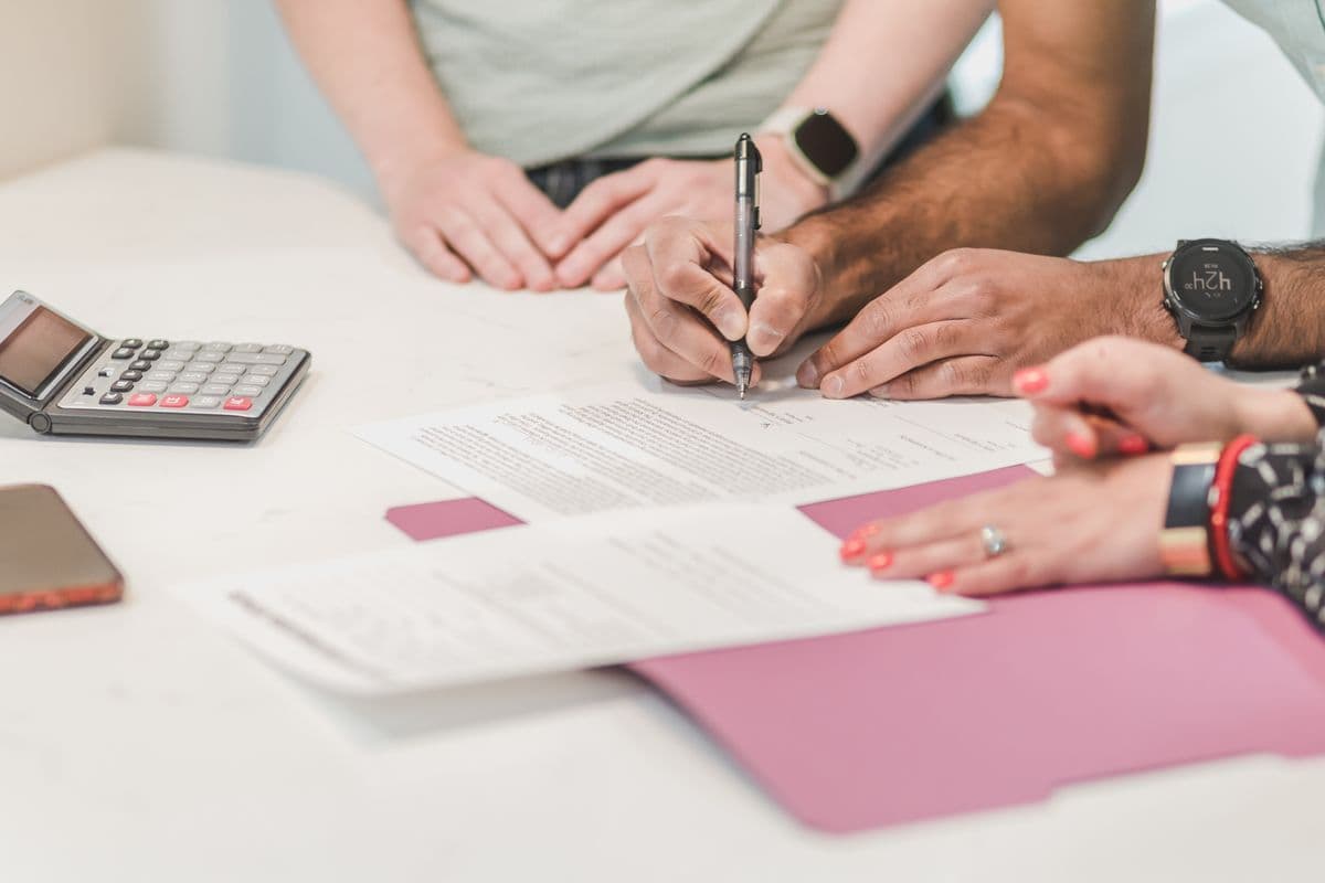 Two people signing a document next to a calculator