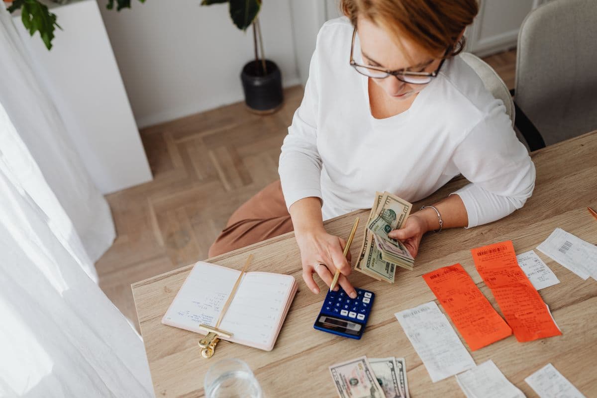 Woman managing finances at home with cash bills and a calculator