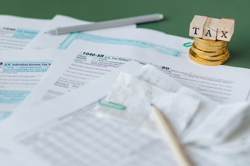 Stack of tax forms and coins with a tax stamp