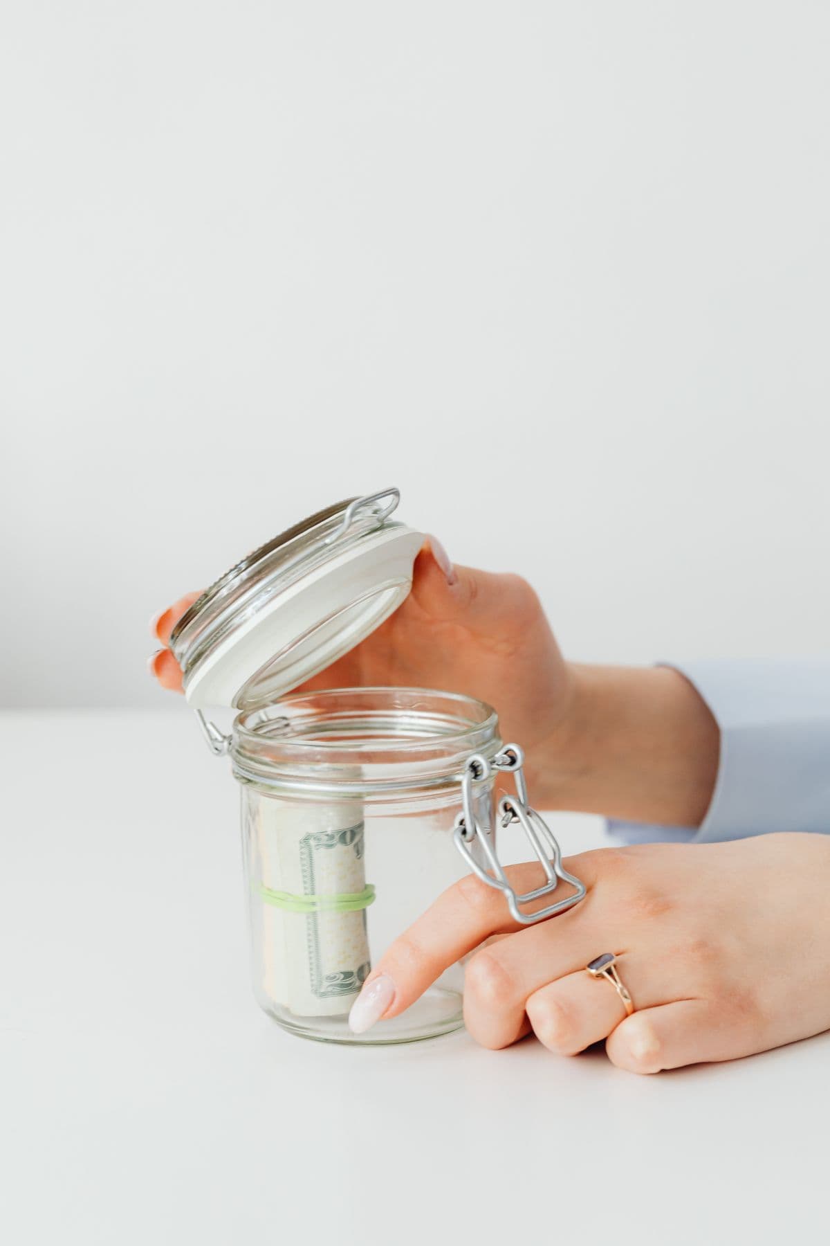 Hands placing coins into a glass savings jar